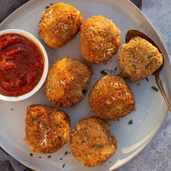 Arancini on a platter with a dipping sauce