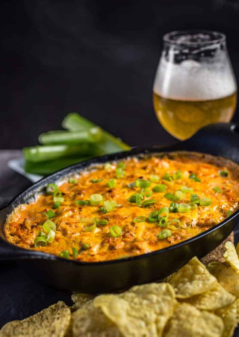 Smoked Buffalo Chicken Dip in a cast iron pan with beer pairing.