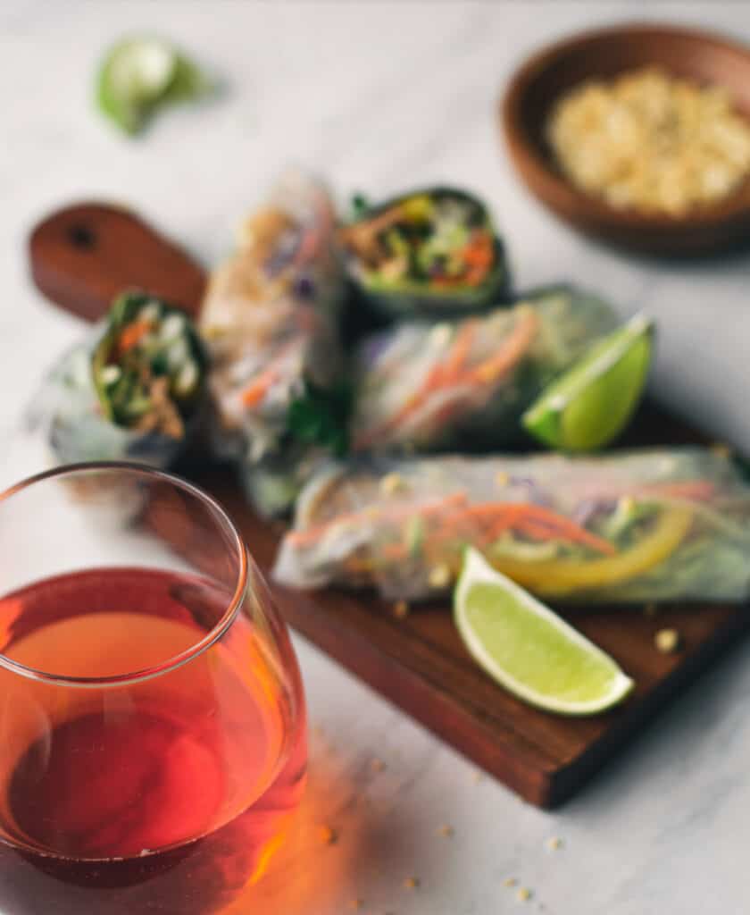 rose wine in front of a board full of spring rolls