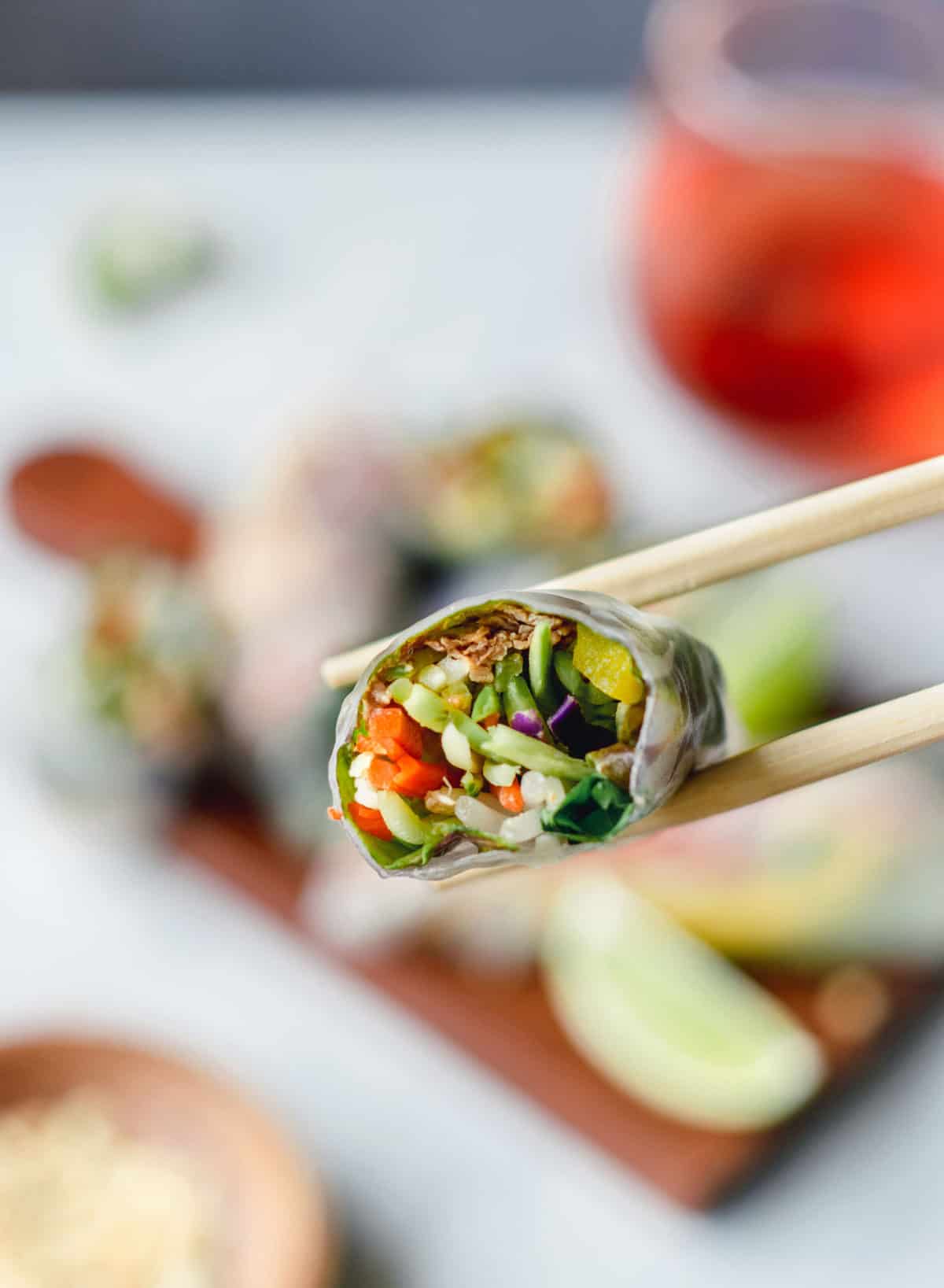 holding a spring roll with chopsticks