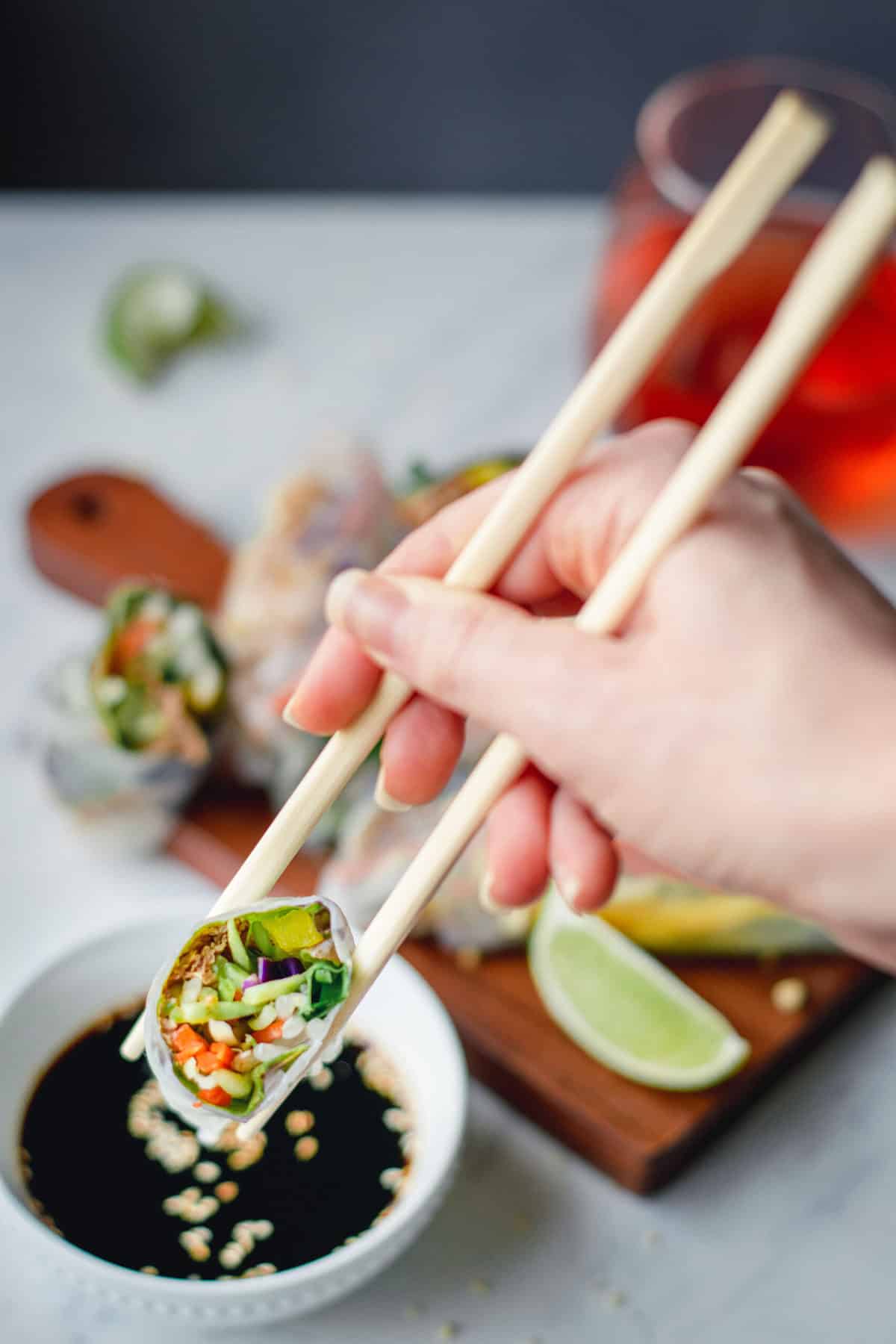 using chopsticks to dip spring roll in soy sauce
