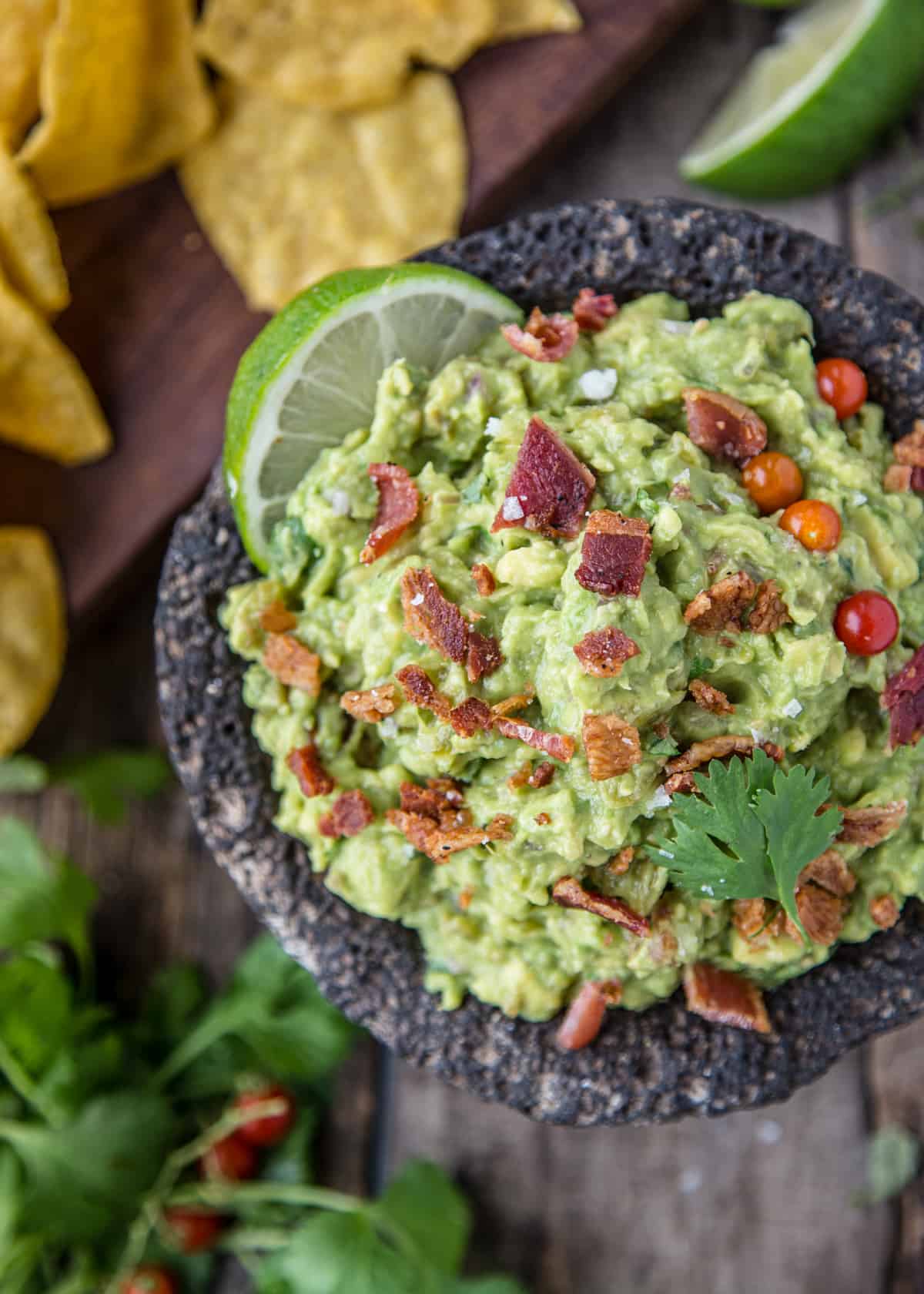 A bowl full of guacamole with smoked bacon and smoked tomatillos