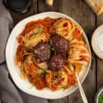 A plate with smoked tomato sauce, pasta, and meatballs