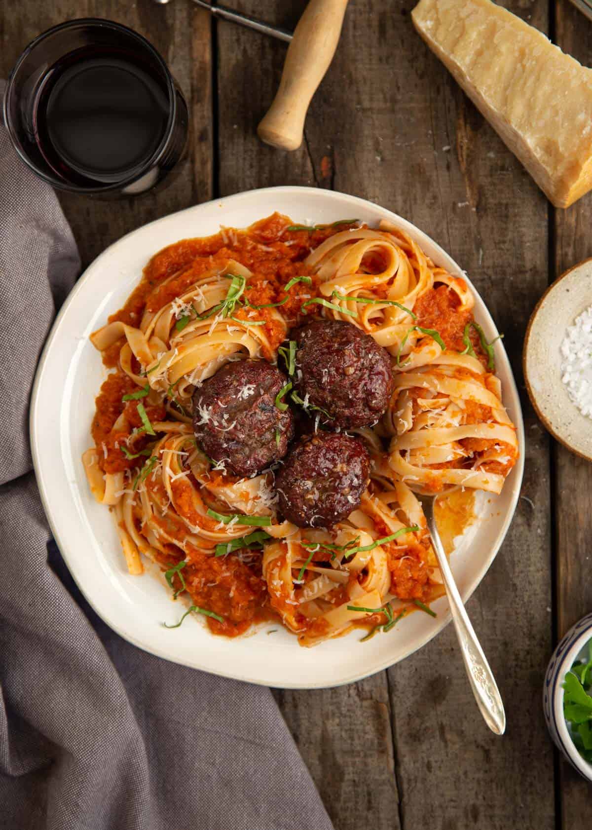 A plate with smoked tomato sauce, pasta, and meatballs