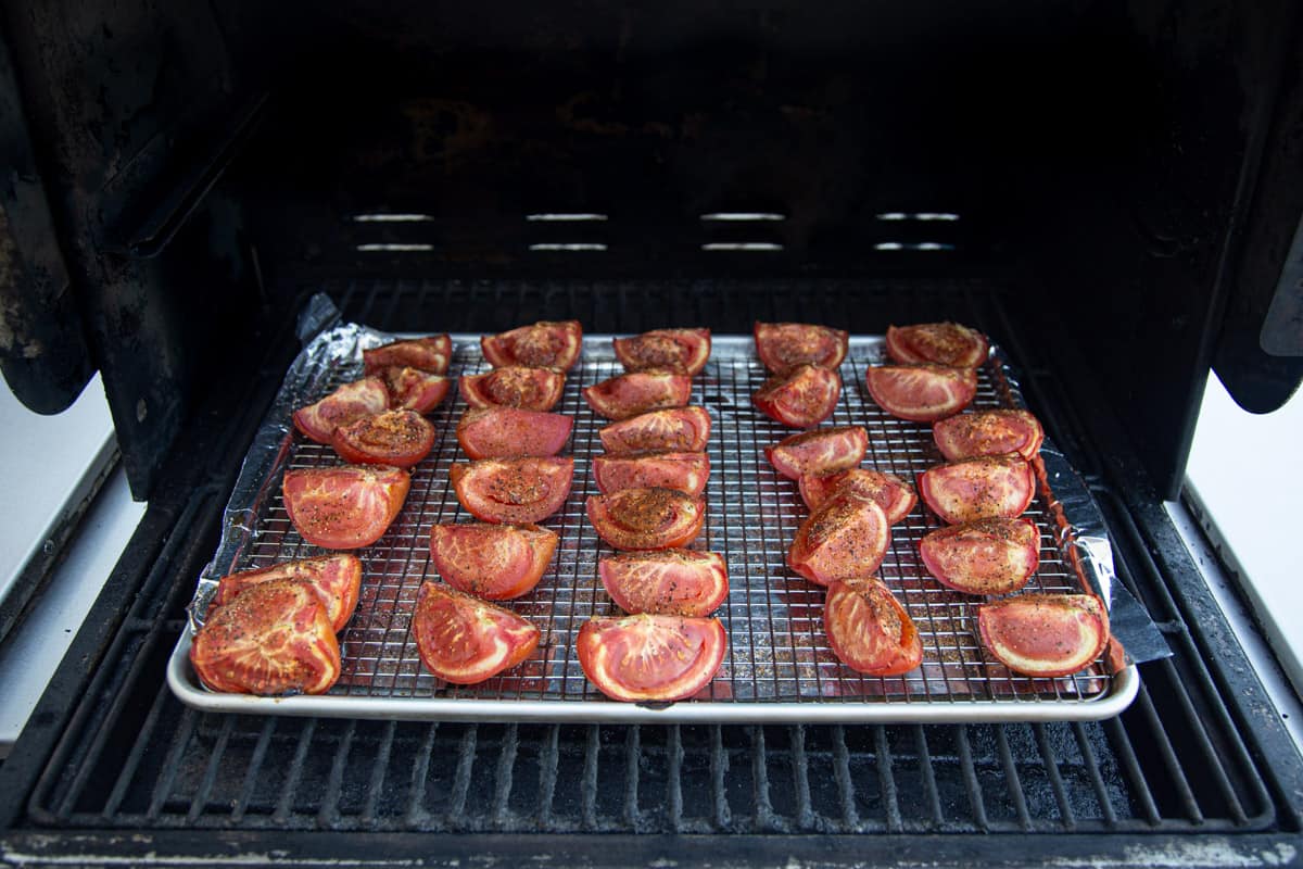 A sheet pan of tomatoes roasting on the grill
