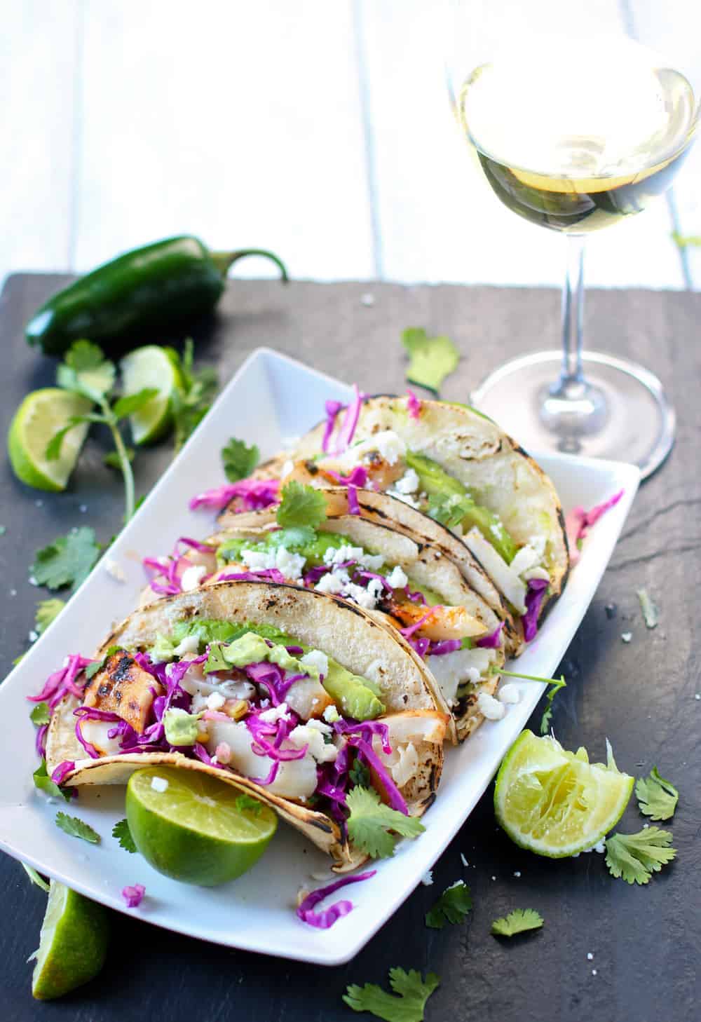 Grilled Fish Tacos on a white plate garnished with limes and cilantro, and Wine Pairing 