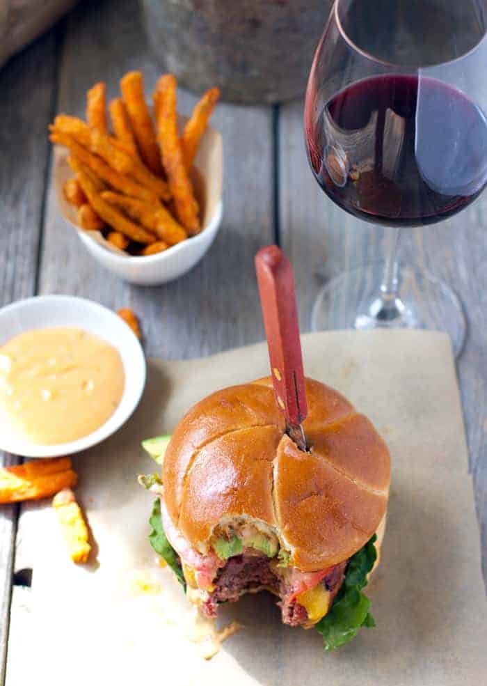 Burger with Chorizo plated with fries and wine.