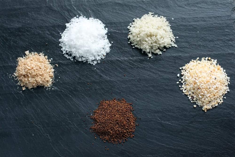 Various styles of kosher and sea salts on a plate.