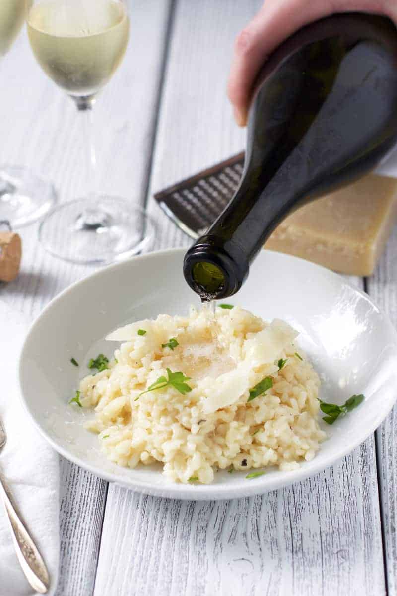 Prosecco being poured into a bowl of risotto
