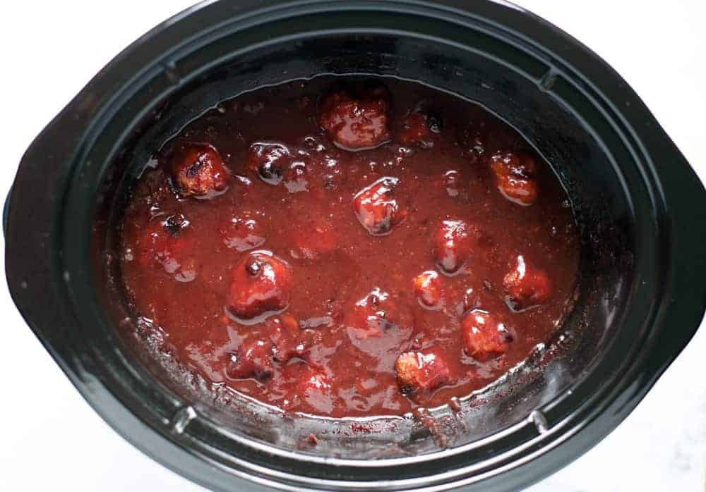 Smoked Meatballs braising in a slow cooker with red wine cranberry sauce