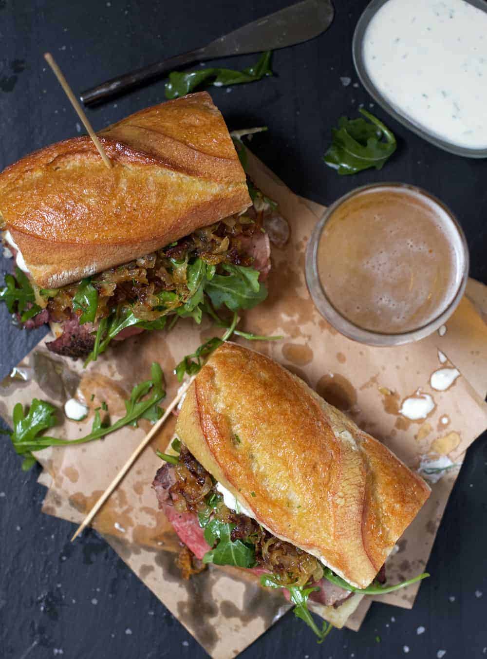 Smoked Prime Rib Steak Sandwiches on parchment paper with a glass of beer 