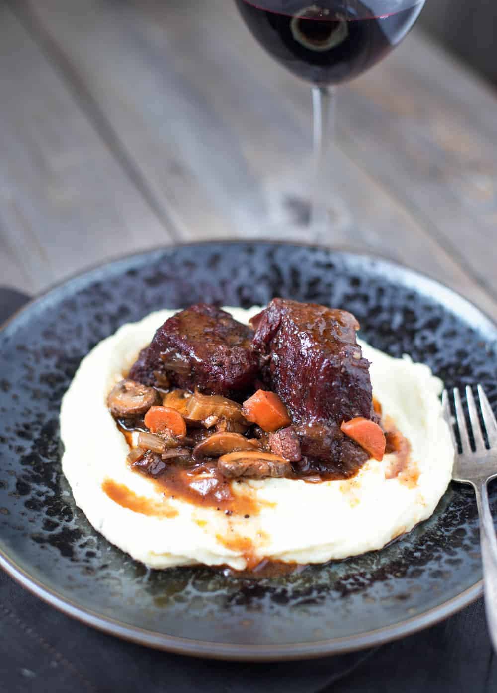A plate of beef stew and a glass of wine