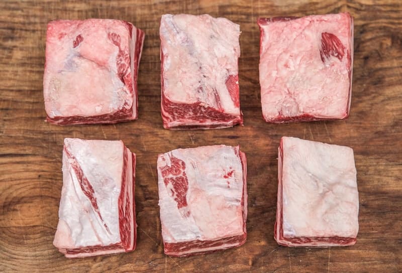 Raw beef short ribs on a wood cutting board