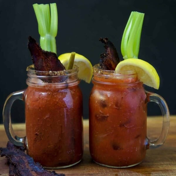 Two glasses with Smoked Bloody Marys garnished with Smoked Bacon