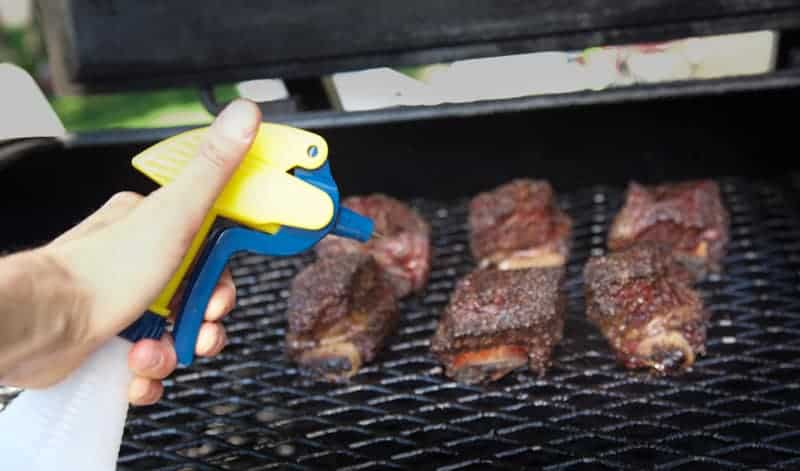 Spritzing meat on the smoker