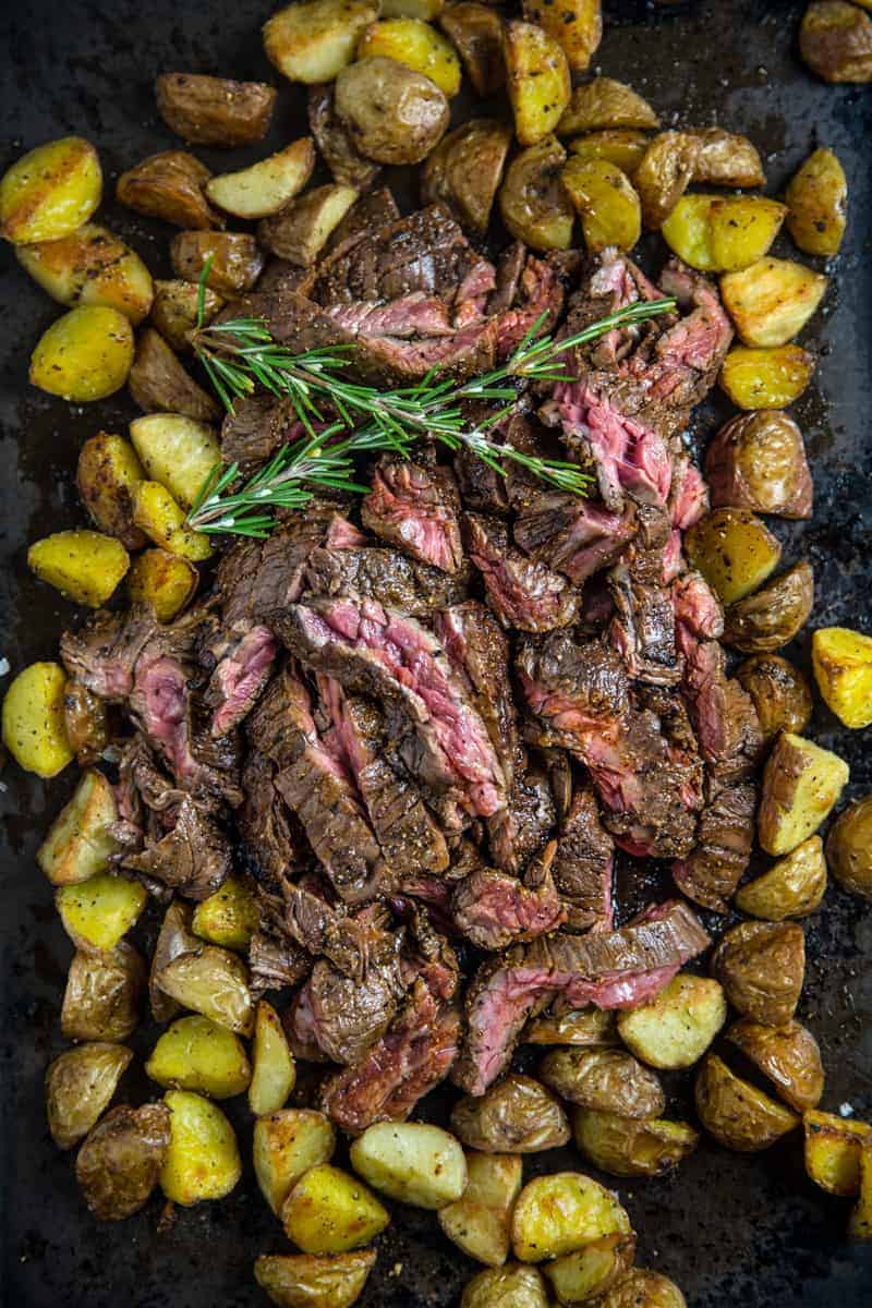 Red Wine Marinated Skirt Steak surrounded by potatoes and garnished with rosemary