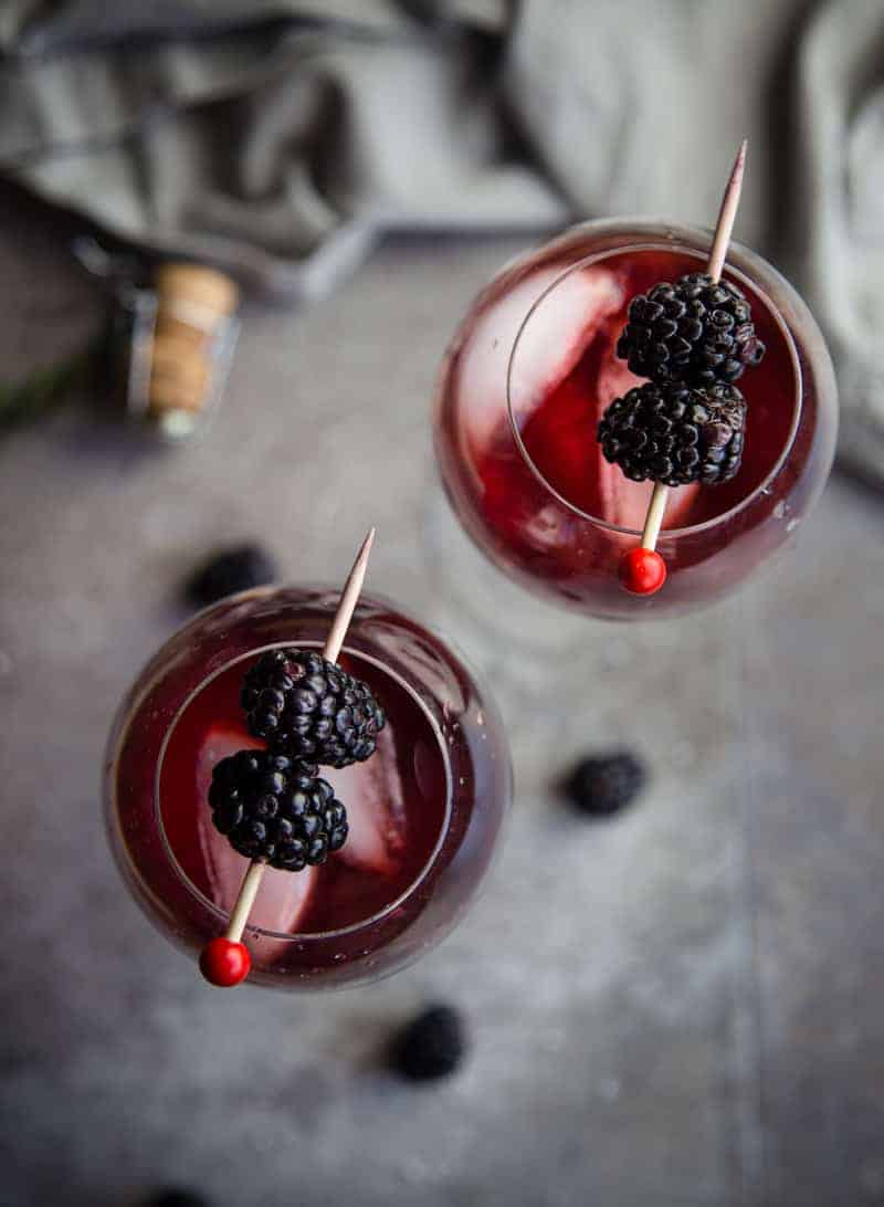 A twist on a classic Aperol Spritz inspired by the Pacific Northwest. Blackberry Aperol Spritz Cocktail, made with blackberry simple syrup. Absolutely gorgeous and elegant. #cocktails #aperolspritz A top down photograph of two glasses filled with Blackberry Aperol Spritz Cocktail