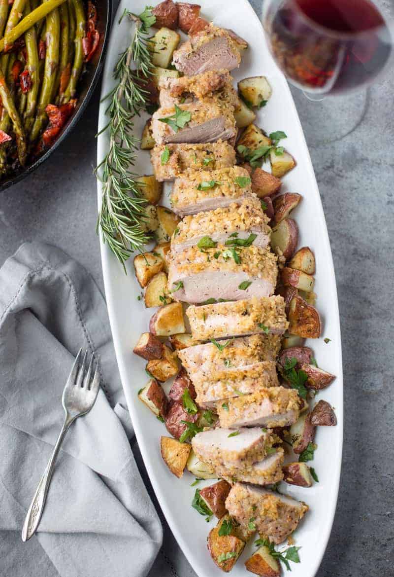 Kettle Chip Crusted Grilled Pork Tenderloin on a platter surrounded by roasted potatoes