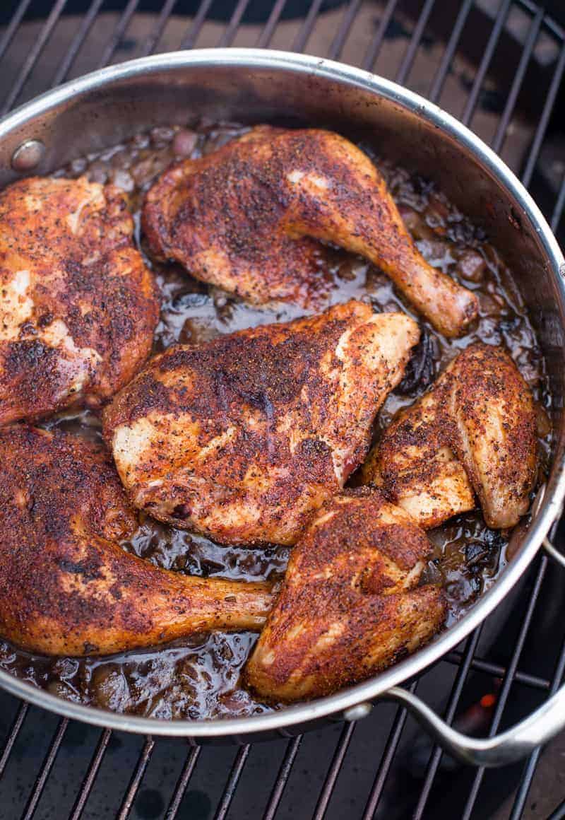 Ancho grilled chicken with prune sauce in a pan on the grill.