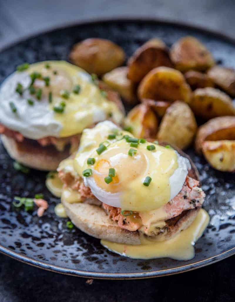 Smoked Salmon Eggs Benedict on a blue plate with roasted potatoes.