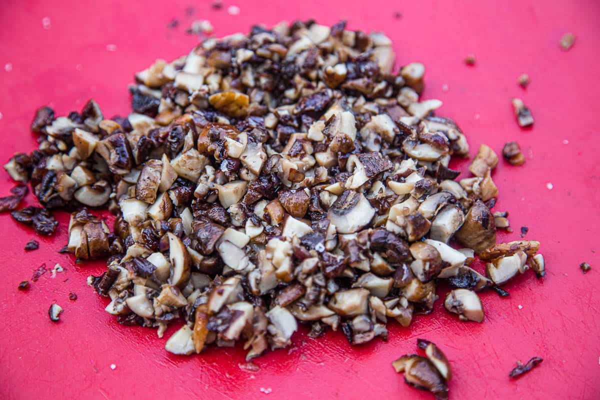 Chopped grilled mushrooms on a cutting board.