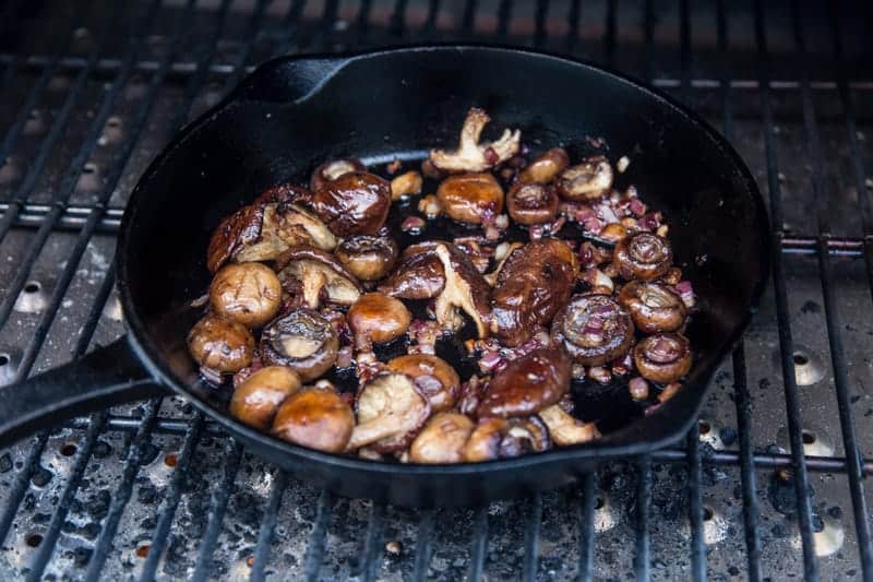 Cooking mushrooms on a grill in a cast iron pan. 