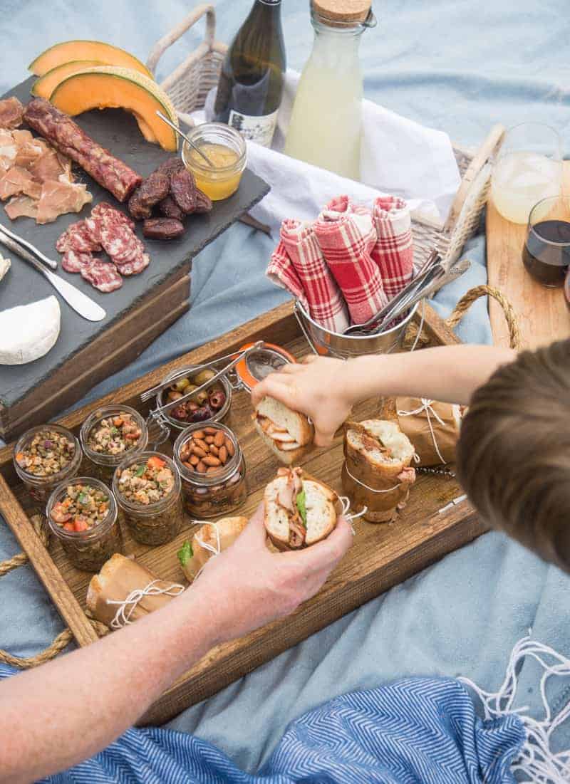 A family eating smoked pork tenderloin sandwiches at a picnic.