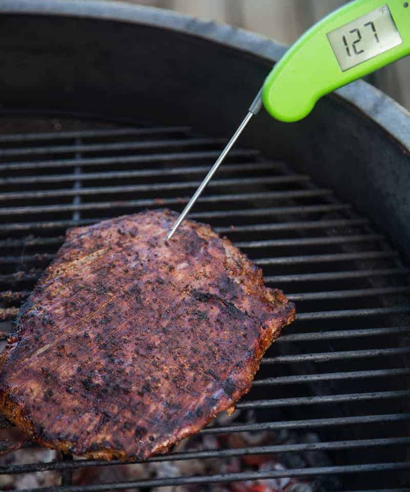 Taking the proper temperature of a grilled flank steak with a digital thermometer
