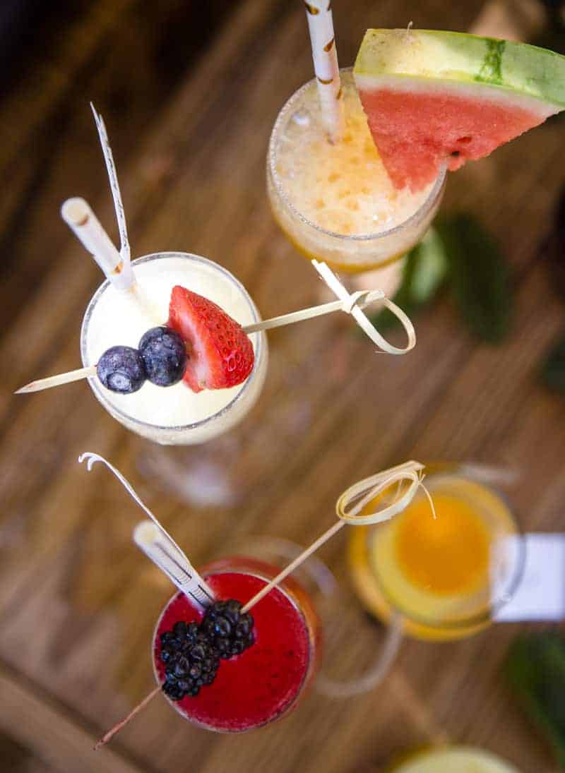 A top down shot of mimosas in flutes with straws and fruit garnishes