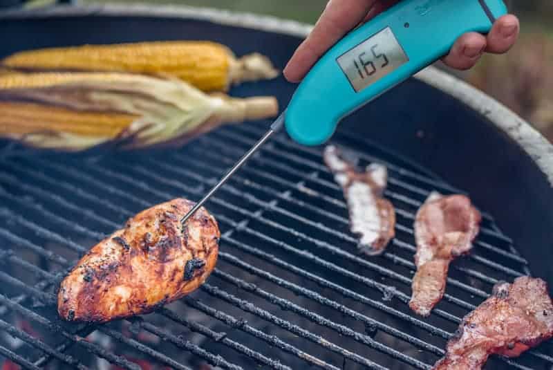 Checking temperature of grilled chicken with a digital thermometer