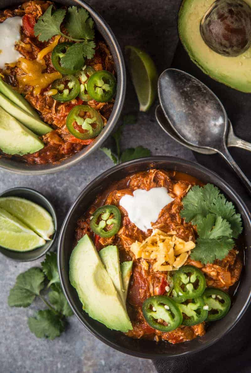 Bowl of Easy Chicken Chili topped with avocado, jalapeño, and shredded cheese