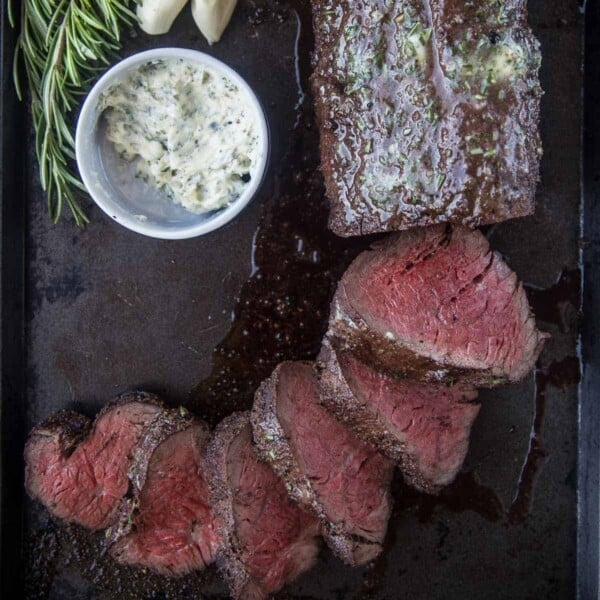 Smoked Beef Tenderloin slices on a serving dish served with a herb butter