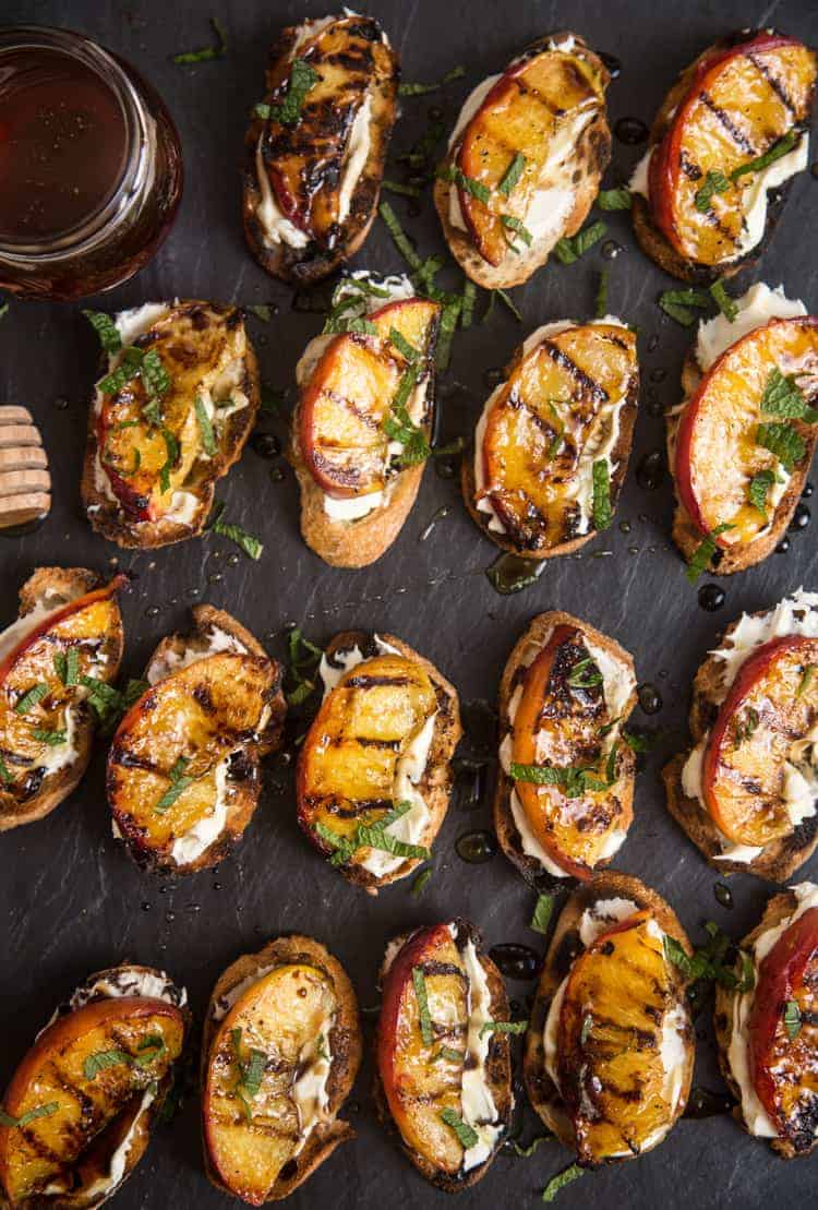 Grilled Peach Crostini topped with Mascarpone and Honey on a black slate platter.