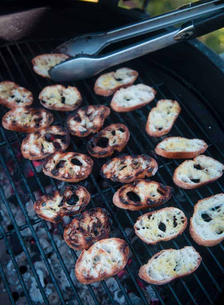 Baguette slices toasting up on a grill.
