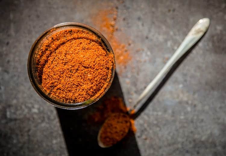 a mason jar filled with seasonings for fish and seafood, orange in color