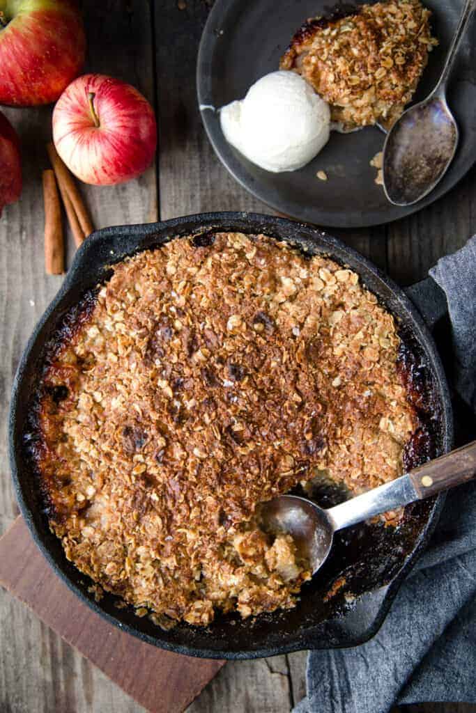 Grilled Apple Crisp in a black pan with a plate of apple crisp and ice cream to the side