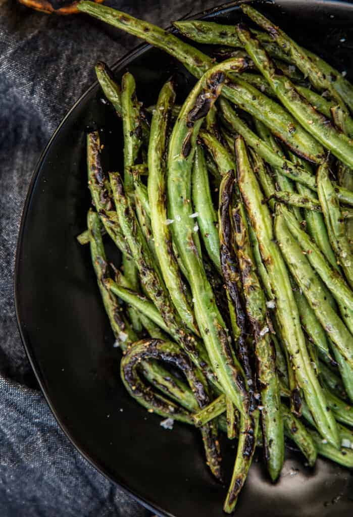 Grilled vegetable side dish, green beans, on a black plate