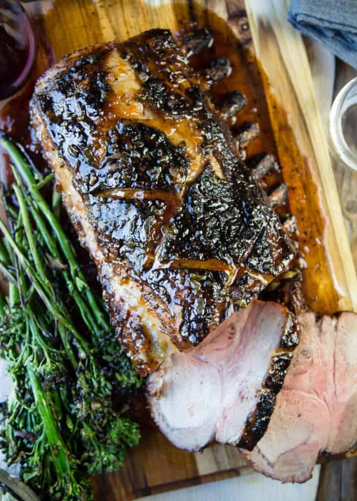 Grilled Pork Roast glazed with Apricot & Herbs on a cutting board with broccolini