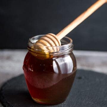 Smoked Honey in a mason jar with a wood honeycomb stick