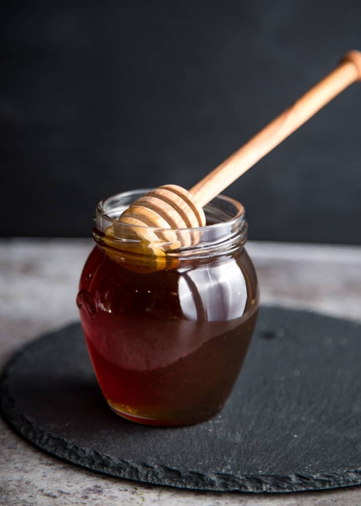 Homemade Smoked Honey in a mason jar with a honey dipper stick