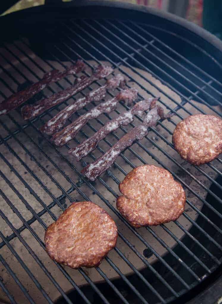 Smoked breakfast sausage and smoked bacon on the smoker grates