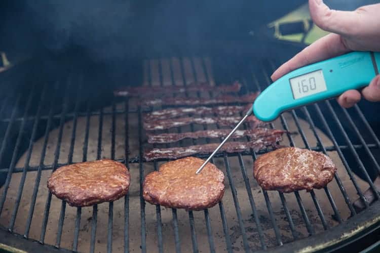 Sausage and Bacon on the grill/smoker with temperature being taken 