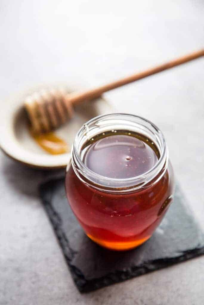Smoked Honey in a mason jar with a honeycomb wood stick. 