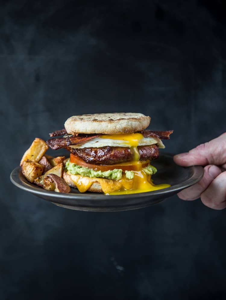 A Breakfast Sandwich with Smoked Sausage and Bacon on a plate.