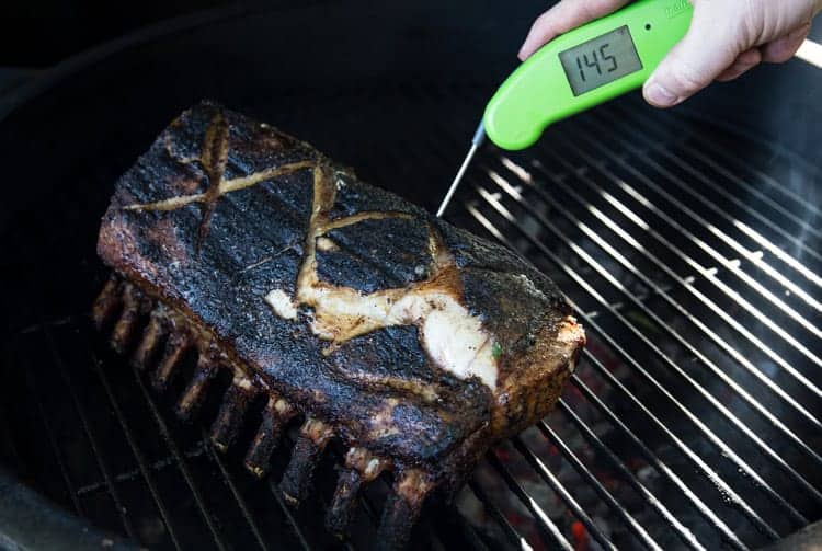 Taking the temperature of the grilled rack of pork with a thermoworks thermapen