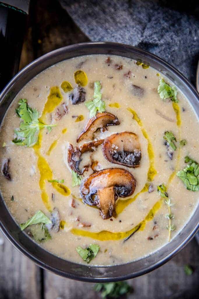 A bowl of mushroom soup topped with fried cremini mushrooms