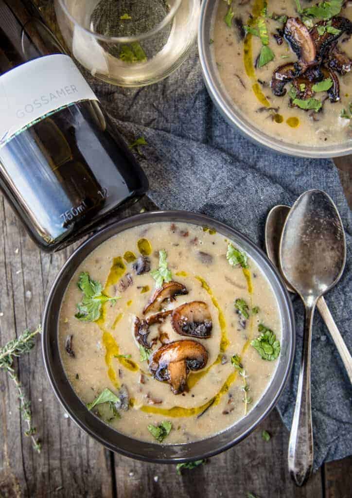Two bowls of Wild Mushroom Soup with a bottle of wine