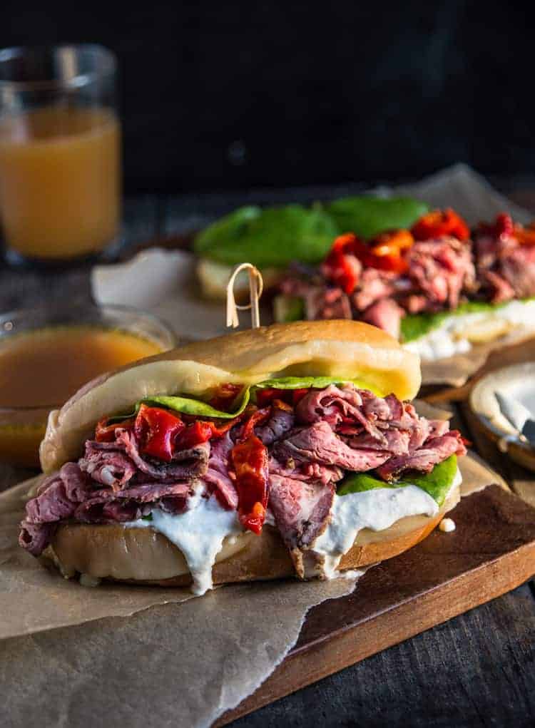 french dip sandwich with cheese, peppers, and sauce