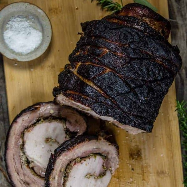 Grilled Porchetta Roast on a cutting board with slices cut showing the filling