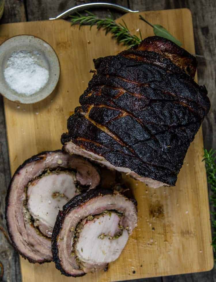 Grilled Porchetta sliced on a cutting board with salt and herbs